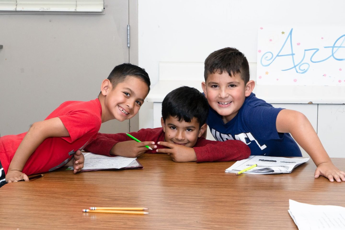 three boys in a classroom with pencils