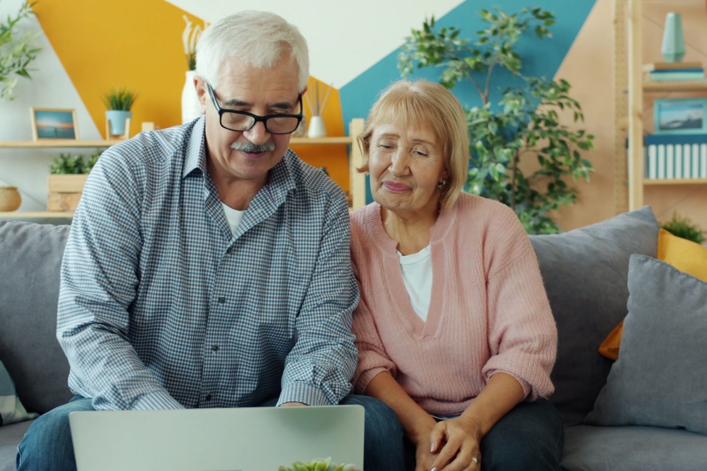 elderly man and woman looking at a laptop