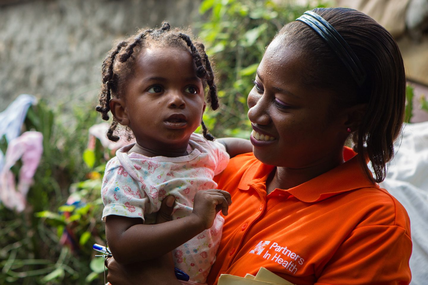 Nurse Asmine Pierre holding a baby during a home visit in Haiti, as part of a childhood malnutrition program.