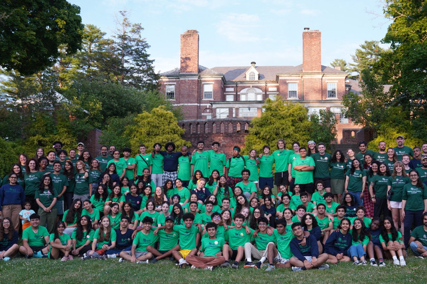 large group of staff and kids on a lawn in front of a building