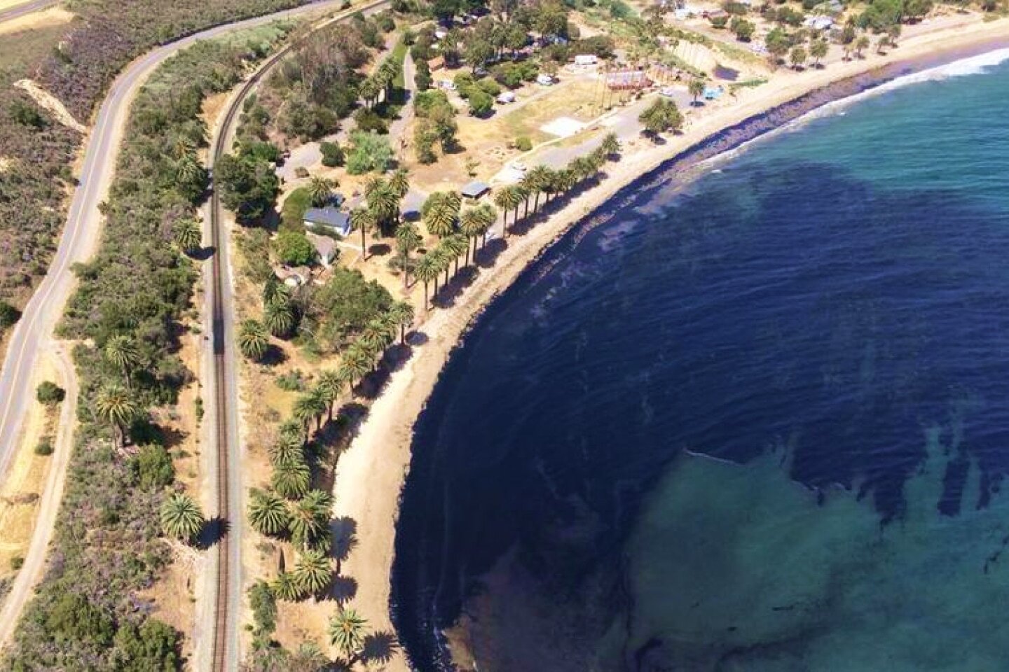 Aerial view of a California coastline with an oil spill