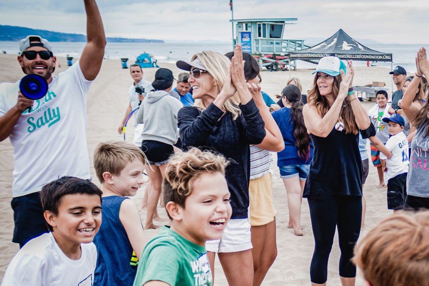 Adults leading a group of children playing on the beach