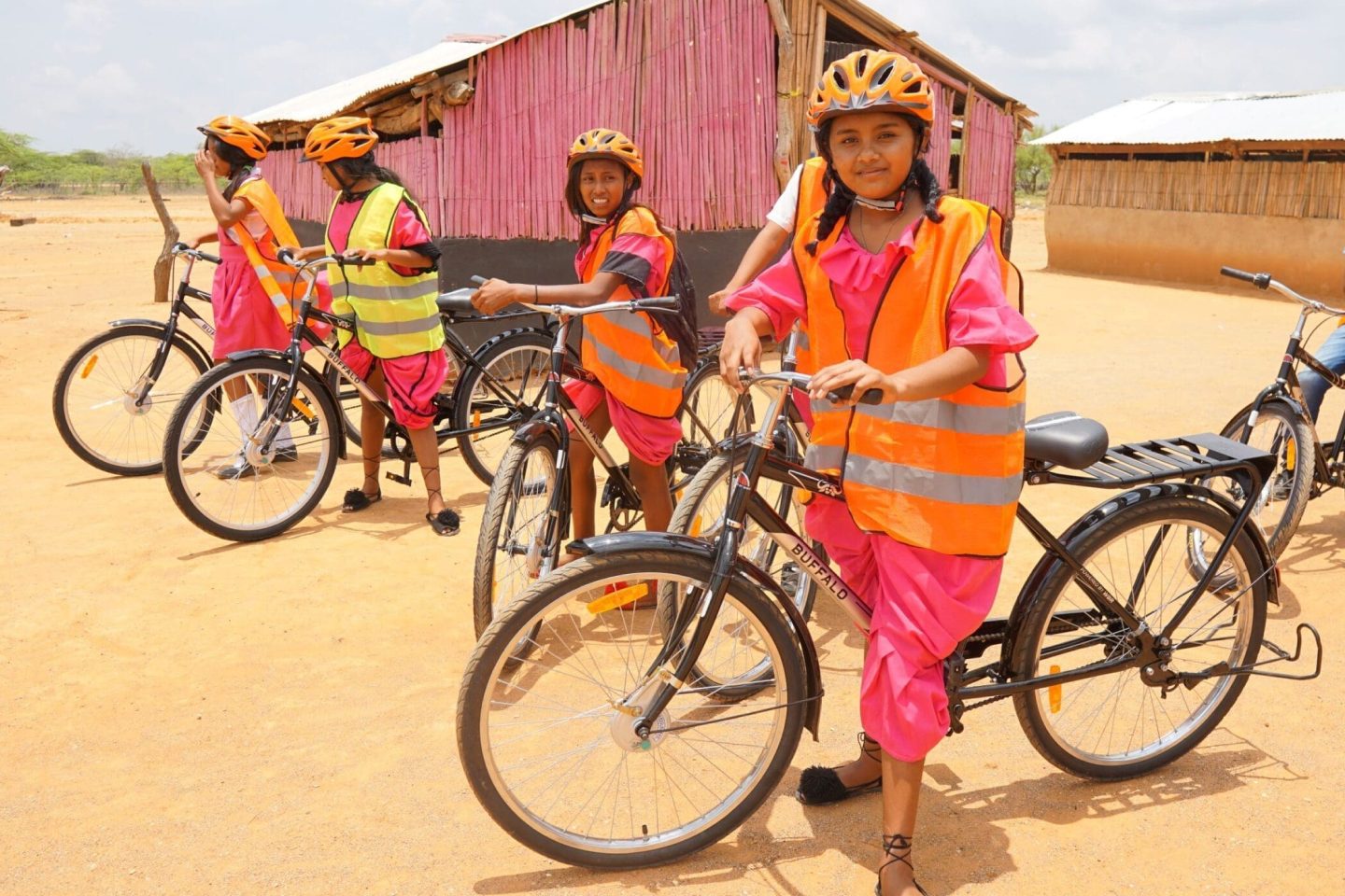 Girls on bikes with safety vests and orange helmets