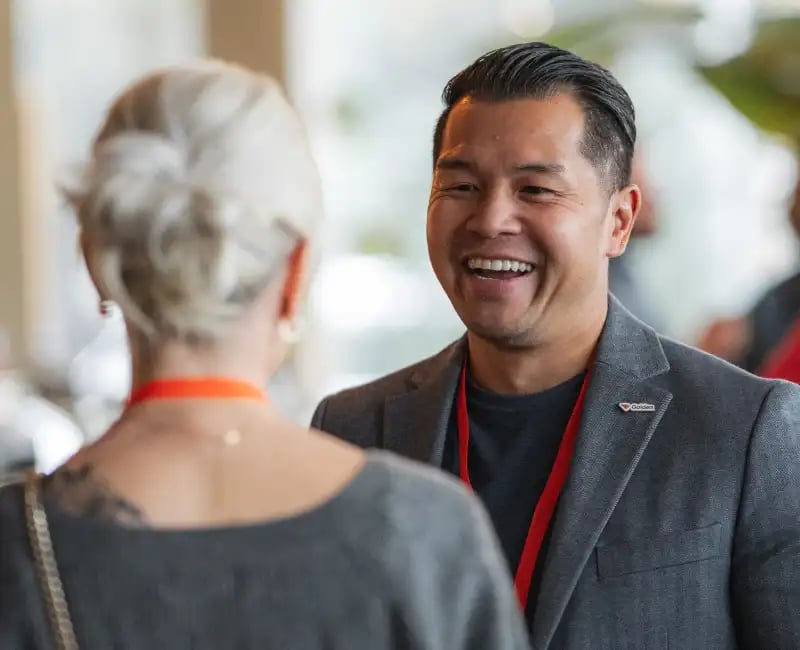 A smiling man networks with a woman