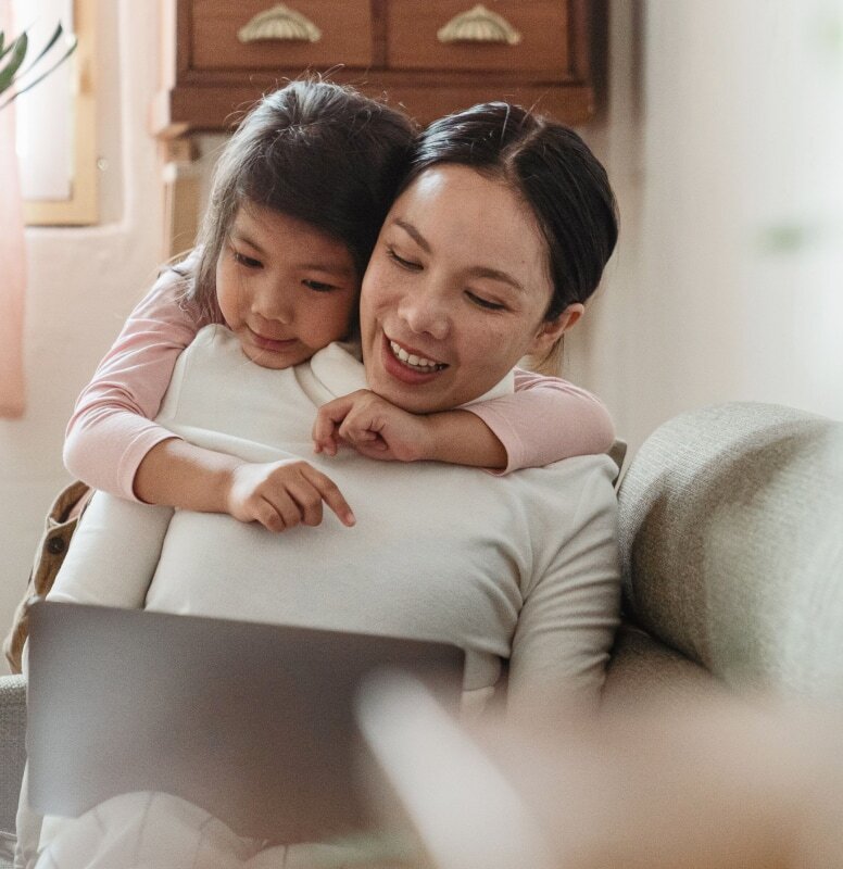 A mother and daughter bonding on the couch in a cozy living room.