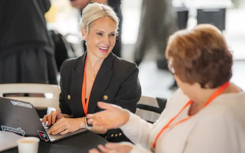 Two attendees talk at a table