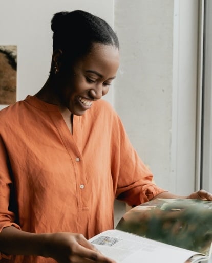 A smiling person flips through a book