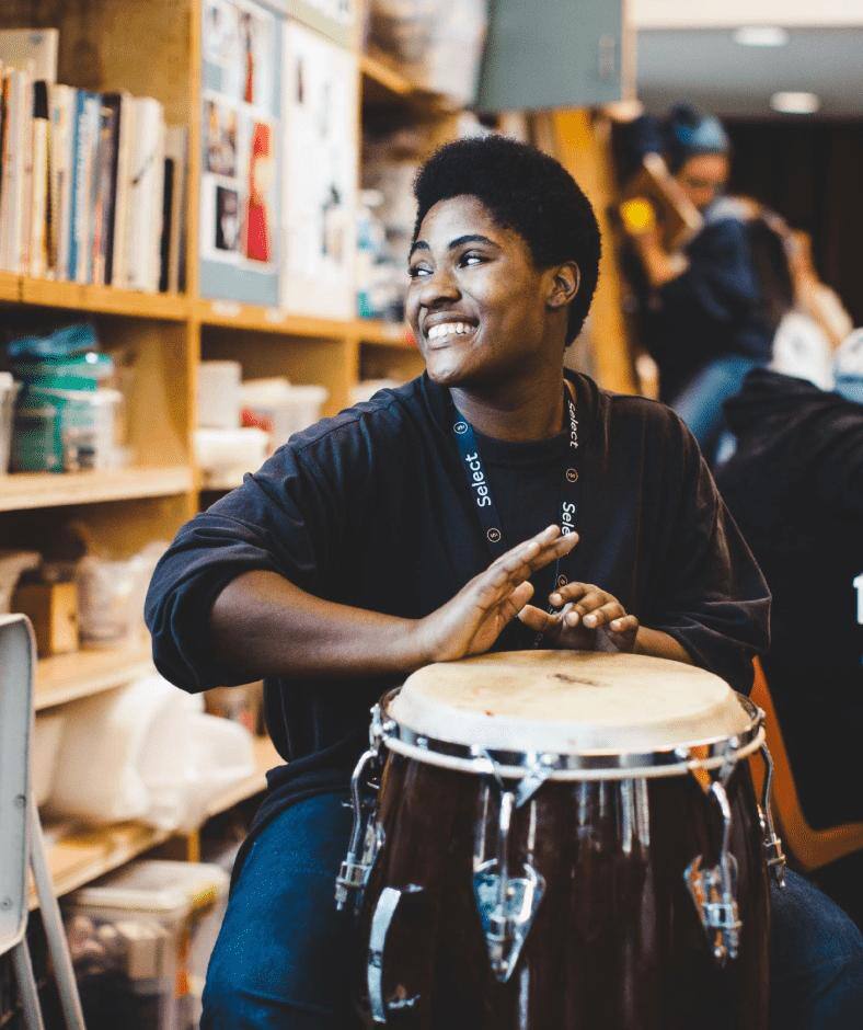 A smiling woman plays a Conga drum