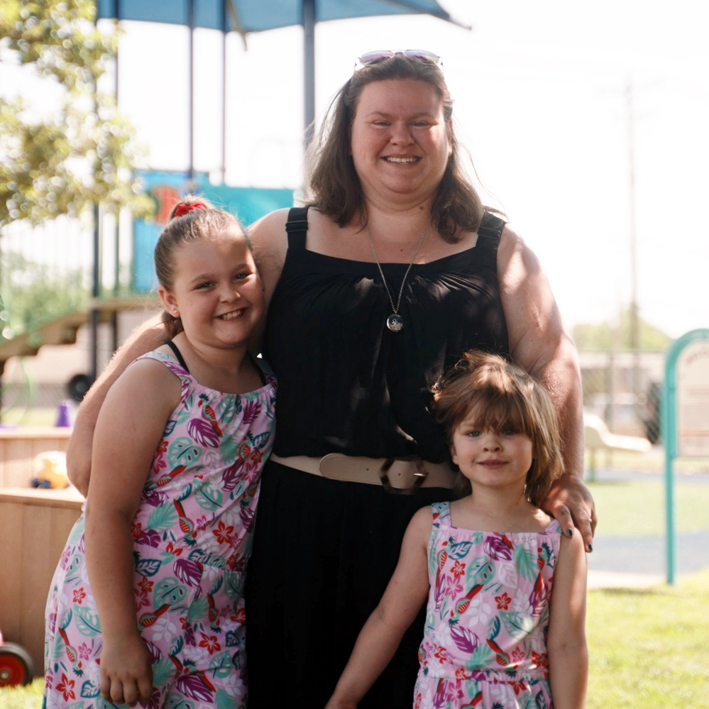 A recipient of UWGC's support hugs her two daughters and smiles.